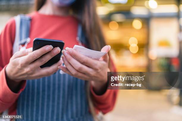 woman checking bill after shopping at supermarket - bonnetje stockfoto's en -beelden