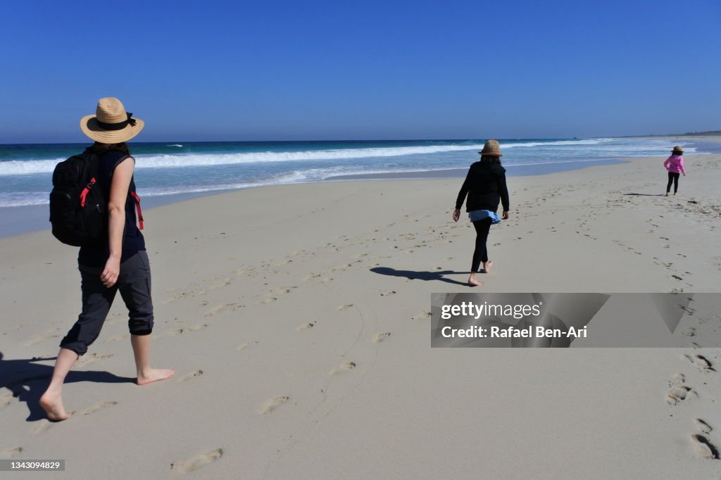 Australian mother and daughters walking along a sandy beach near Perth Western Australia