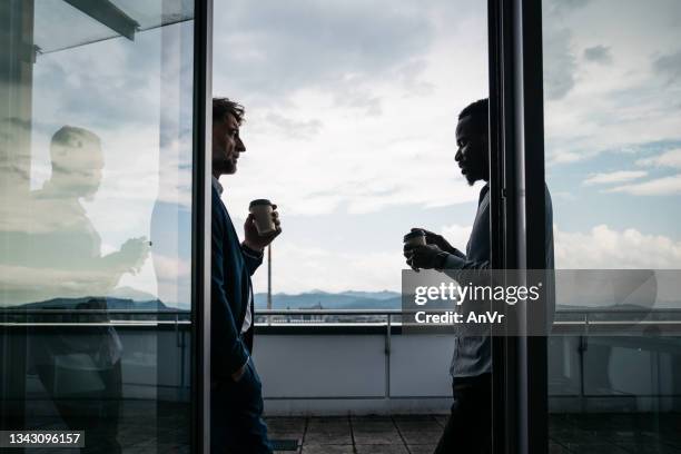 zwei mitarbeiter gönnen sich eine kaffeepause auf einer terrasse - sliding door stock-fotos und bilder