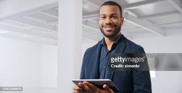 homme d’affaires debout avec une tablette numérique au bureau - black blazer photos et images de collection