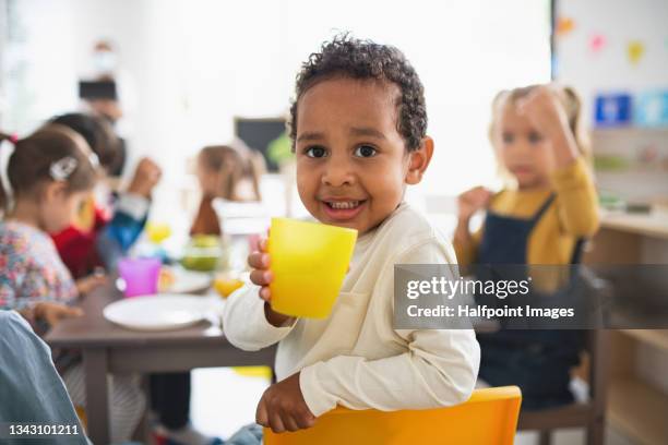 pre school multiracial boy having meal with children indoors at nursery school, looking at camera. - school bus stock photos et images de collection