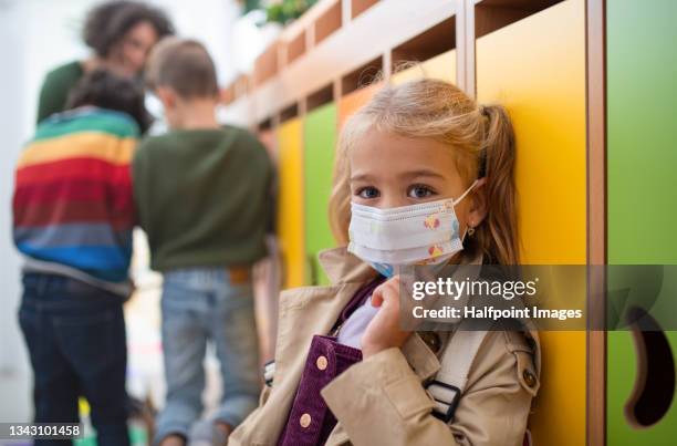 pre school girl with face mask sitting indoors in cloakroom at nursery, coronavirus concept. - young boys changing in locker room 個照片及圖片檔