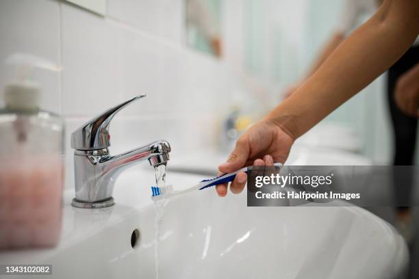 cropped hand of child holding toothbrush under running water indoors in nursery. - bathroom sink stock pictures, royalty-free photos & images