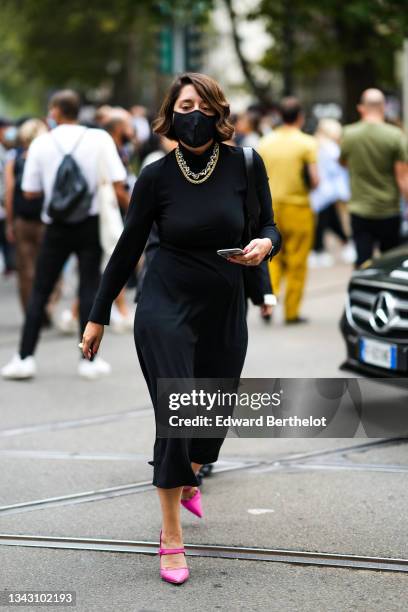 Guest wears a black long turtleneck wool pullover, large black knees pants, a black shiny leather watch, rings, neon pink shiny pointed pumps heels...