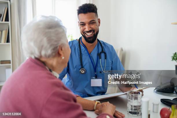 healthcare worker or caregiver visiting senior woman indoors at home, explaining. - home health - fotografias e filmes do acervo