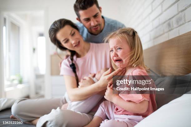 happy young parents consoling little daughter at home. - moms crying in bed stockfoto's en -beelden