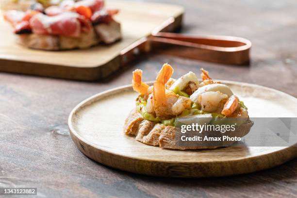 assorted bruschetta with shrimp, avocado guacamole, mozzarella cheese, sun-dried tomatoes, prosciutto in high key style on wooden table background. - crostini stock pictures, royalty-free photos & images