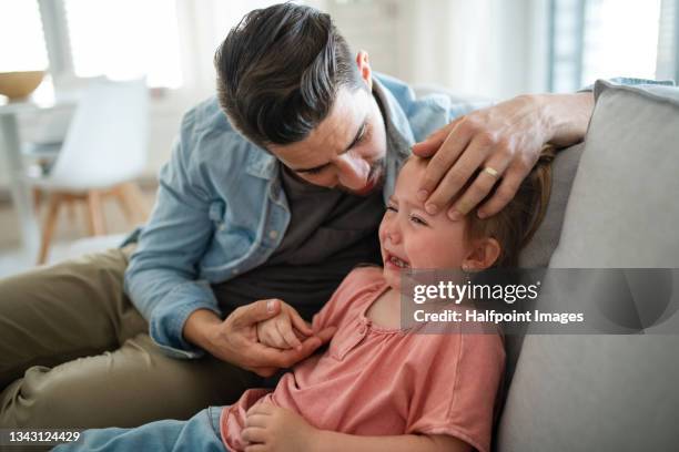 young father consoling his little daughter at home. - trotzanfall stock-fotos und bilder