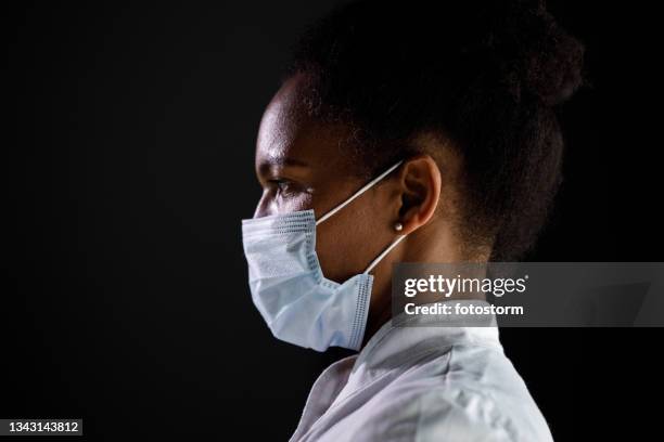 headshot of female doctor in a protective face mask - protective face mask side stock pictures, royalty-free photos & images