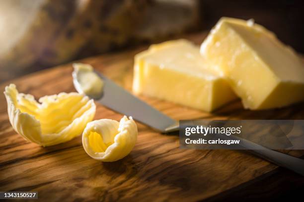 butter curl and butter knife on a wooden cutting board - butter knife stock pictures, royalty-free photos & images