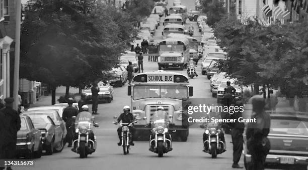 Accompanied by motorcycle-mounted police, school buses carrying African American students arrive at formerly all-white South Boston High School on...