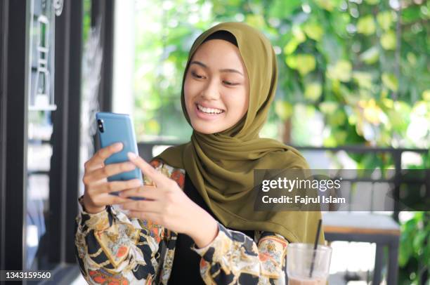 young woman using smartphone for teleconferencing - archipiélago malayo fotografías e imágenes de stock