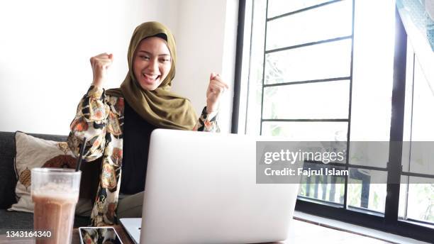 excitement asian muslim young woman with laptop - excitement laptop stock pictures, royalty-free photos & images