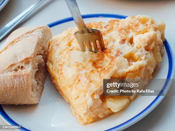 slice of potato omelette (spanish "tortilla de patatas") with some bread - tortilla de patata fotografías e imágenes de stock