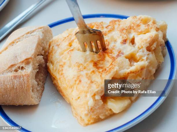 slice of potato omelette (spanish "tortilla de patatas") with some bread - tortilla de patatas photos et images de collection