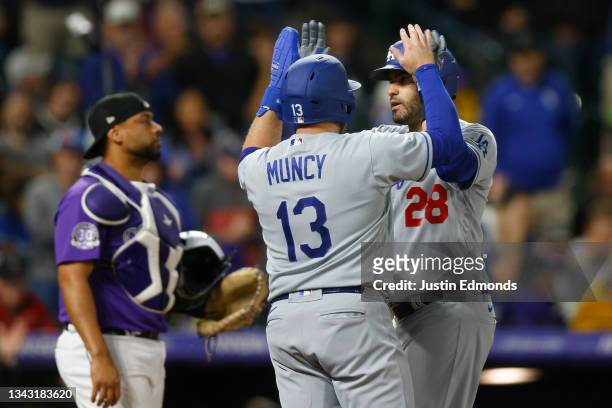 Martinez of the Los Angeles Dodgers celebrates his two-run home run with Max Muncy as catcher Elias Diaz of the Colorado Rockies looks on in the...