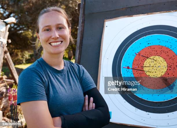 cropped portrait of an attractive young female archer practicing her craft out on the archery range - bulls eye stock pictures, royalty-free photos & images