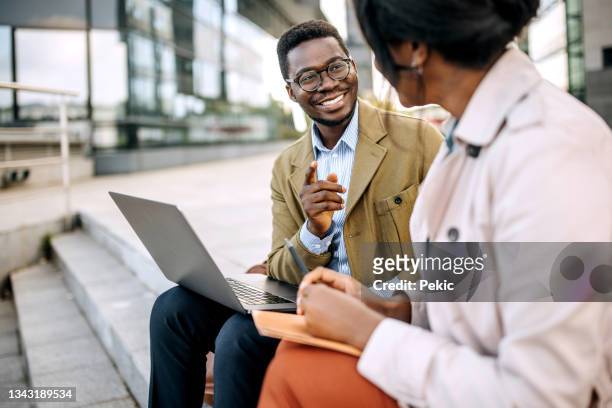 young business partners sitting on stairs in front of their company - business casual outside stock pictures, royalty-free photos & images