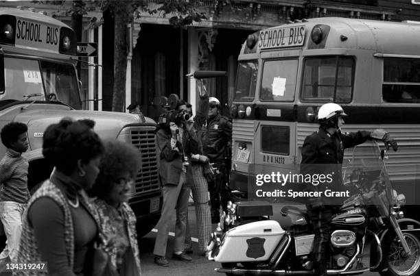 Accompanied by motorcycle-mounted police, school buses carrying African American students arrive at formerly all-white South Boston High School on...