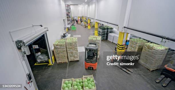 male worker using forklift truck in warehouse - forklift truck warehouse stock pictures, royalty-free photos & images