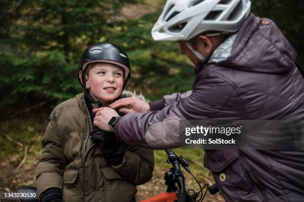 getting help from dad - father helping son wearing helmet stock pictures, royalty-free photos & images