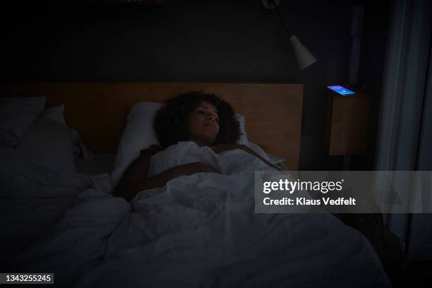 woman sleeping by smart phone with alarm ring - woman 45 sleeping stock-fotos und bilder