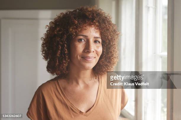 smiling woman with curly brown hair - cerca de fotografías e imágenes de stock