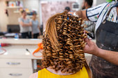 Close up hands of a hairdresser and treatment to a curly red hair woman