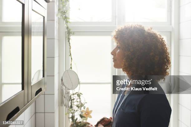 nurse looking in mirror while getting dressed - woman mirror stockfoto's en -beelden