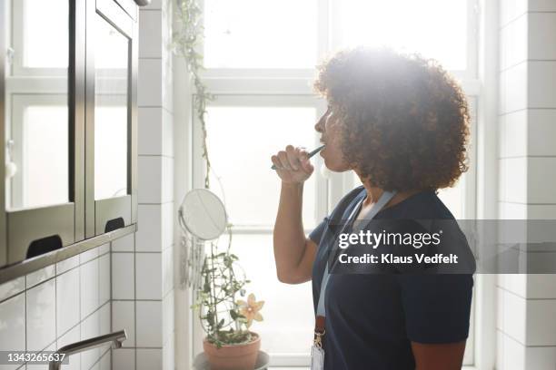 healthcare worker brushing teeth in bathroom - tandpasta stockfoto's en -beelden