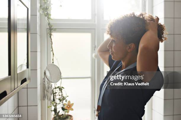 home caregiver tying hair - side view mirror foto e immagini stock