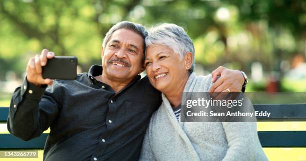 shot of an elderly couple taking a selfie while sitting on a bench in a park - photographing garden stock pictures, royalty-free photos & images