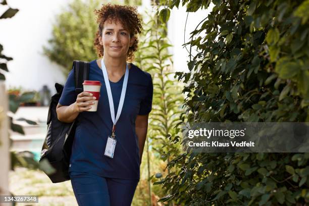 caregiver with reusable cup walking by plants - trageschnur stock-fotos und bilder