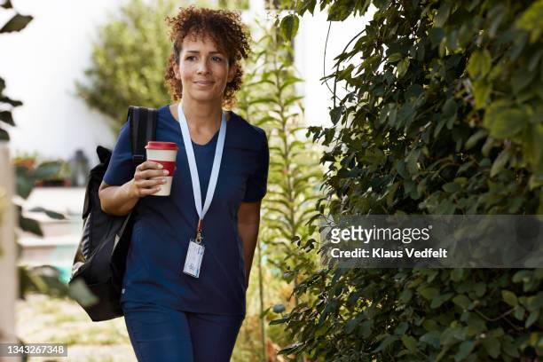 caregiver with reusable cup walking by plants - ネックストラップ ストックフォトと画像