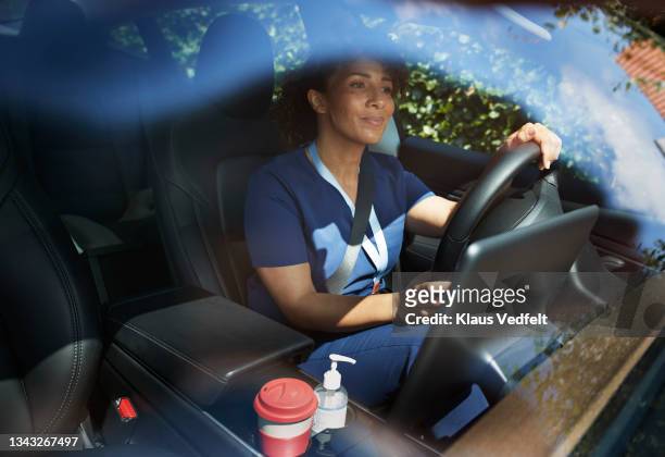 female healthcare worker driving car - pflegedienst blau stock-fotos und bilder