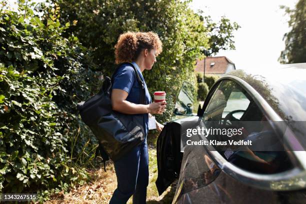 healthcare worker opening door of car - commuter stockfoto's en -beelden
