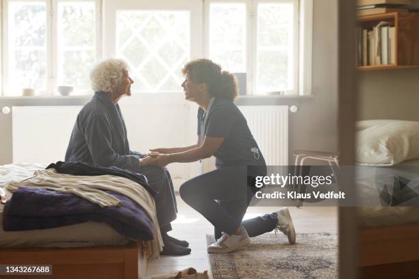 caregiver holding hands of senior woman - pflegedienst blau stock-fotos und bilder