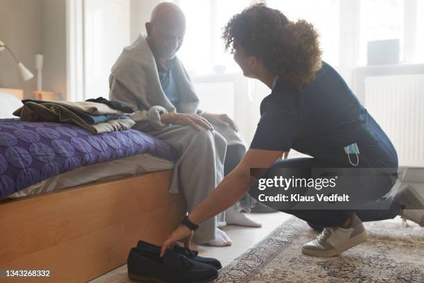 man looking at female caregiver holding shoe - help getting dressed stock pictures, royalty-free photos & images