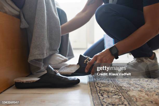 female nurse helping senior man wearing shoe - weakness stock pictures, royalty-free photos & images