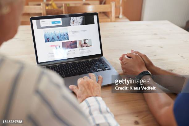 woman learning to book appointment from caregiver - using computer stock-fotos und bilder