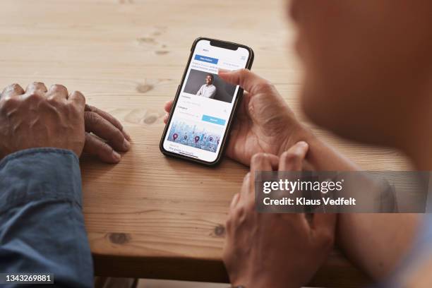 healthcare worker teaching smart phone to man - mobile device on table stock-fotos und bilder