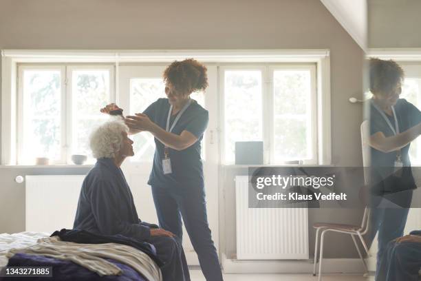 healthcare worker combing senior woman hair - combing stock pictures, royalty-free photos & images