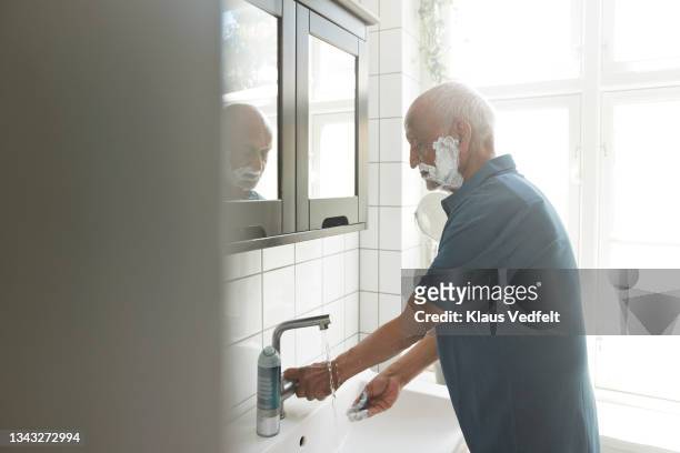 senior man washing hands in bathroom - shaving cream stock-fotos und bilder