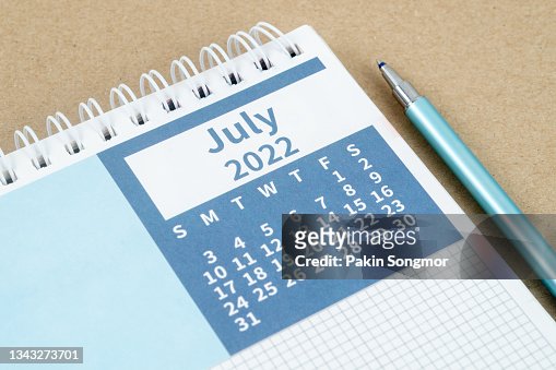 Calendar desk 2022 on July month, Top view calendar planning and pen on gray paper background.