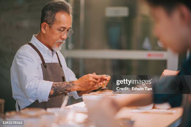 asian chinese senior man barista connoisseur scooping coffee ground cleaning for coffee cupping tasting scope - arabica coffee drink stock pictures, royalty-free photos & images