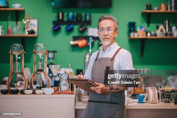 portrait asian chinese working senior man barista at cafe bar counter looking at camera smiling - connoisseur stock pictures, royalty-free photos & images