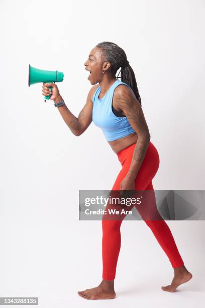 mature woman in sports clothing shouting into  megaphone - multi coloured megaphone stock pictures, royalty-free photos & images