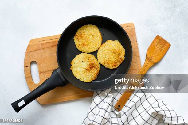 golden potato pancakes or draniki are fried in a frying pan, at home, in the kitchen. preparing a delicious breakfast or lunch. the concept of vegetarian and vegan food and diet. homemade food, diy. - american pancakes stock pictures, royalty-free photos & images