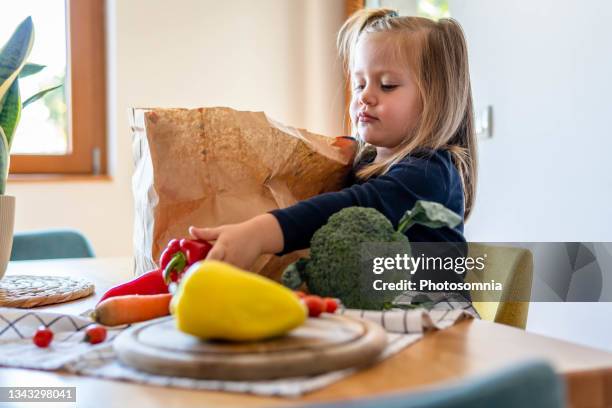 cute girl unloads vegetables from paper bag - offloading stock pictures, royalty-free photos & images