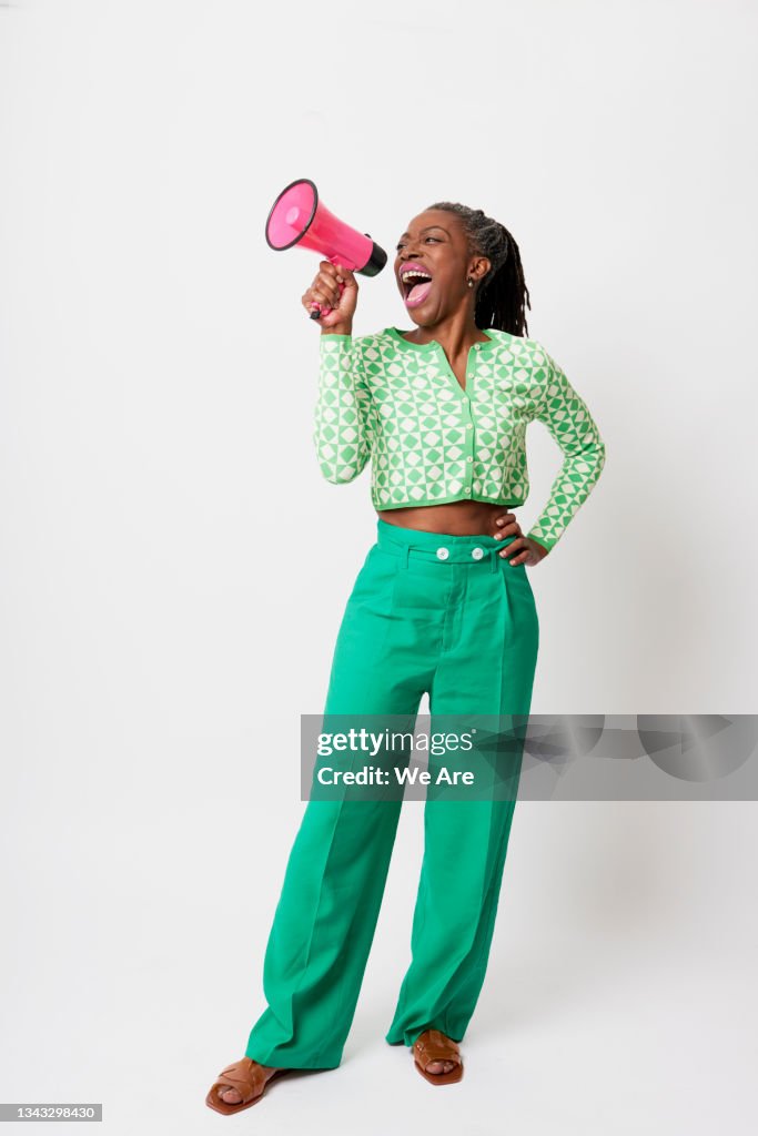 Full length portrait of mature woman shouting a message through a megaphone
